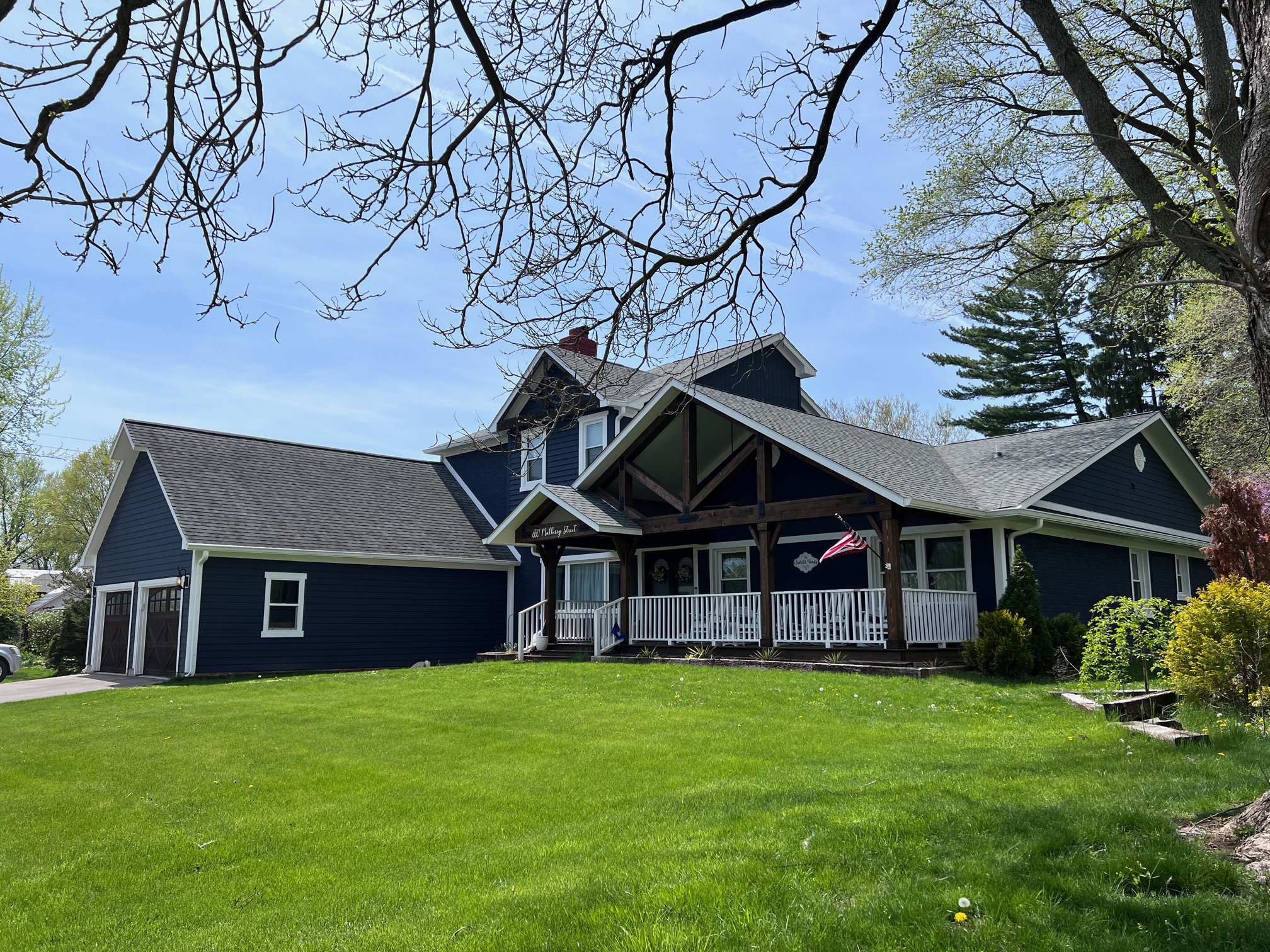 a home with dark navy siding, a white deck railing and white window frames, creating bold contrast