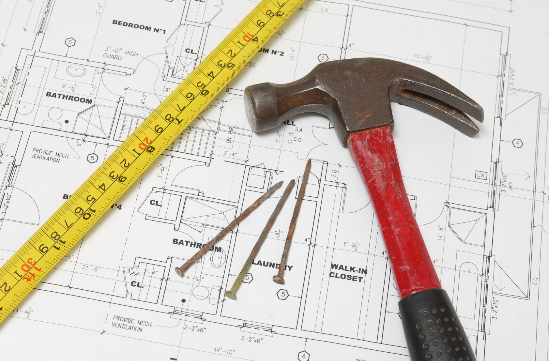 remodel blueprints with a hammer and tape measure on top