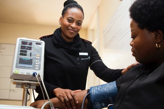 A healthcare professional is taking the blood pressure of a seated patient.
