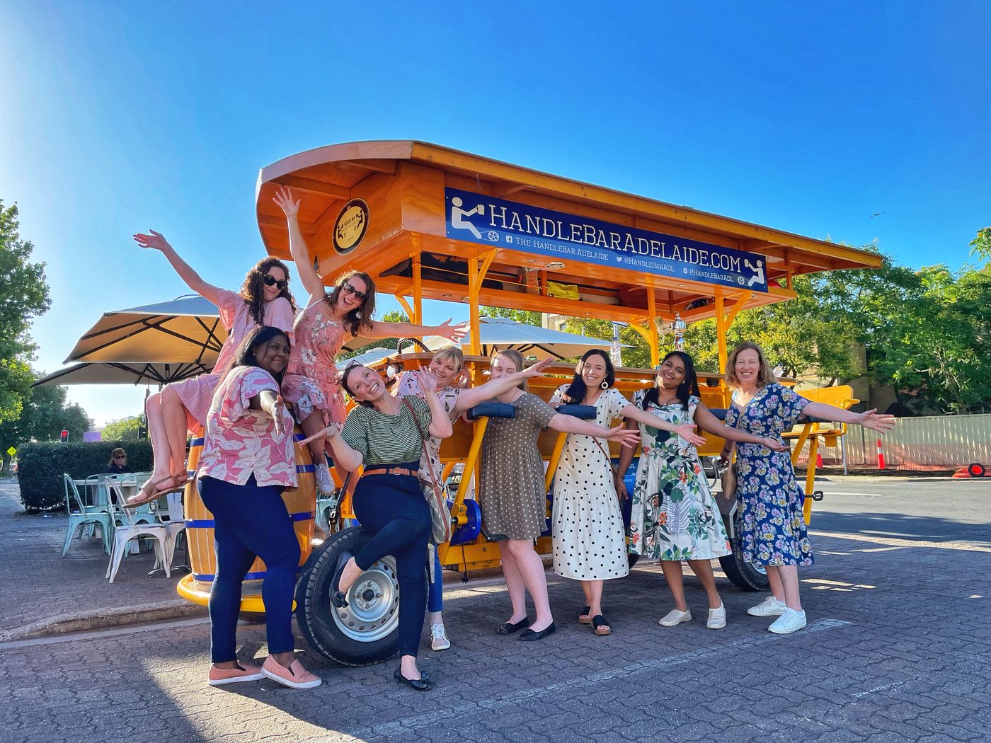A group of riders posing with arms outstretched in front of the HandleBar pedal bike