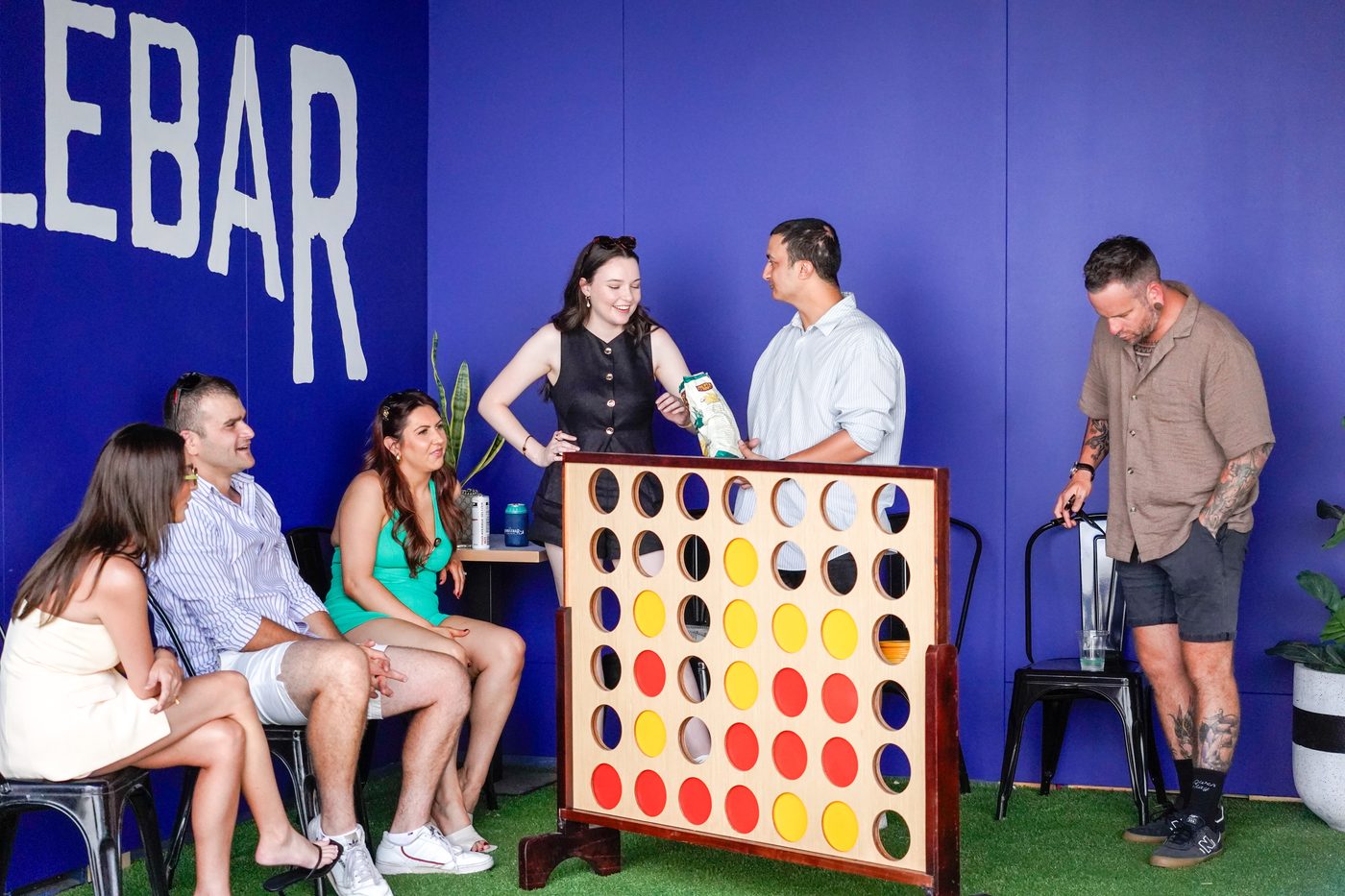Guests playing giant Connect Four against the blue HandleBar wall at HomeBase