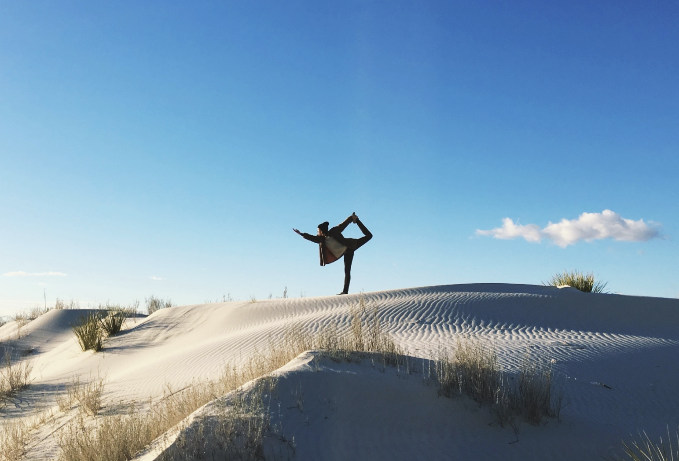 image of person doing yoga pose on sandy landscape