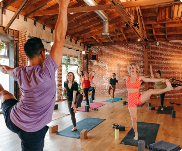 image of a yoga class with students laughing and balancing at a yoga studio in Echo Park