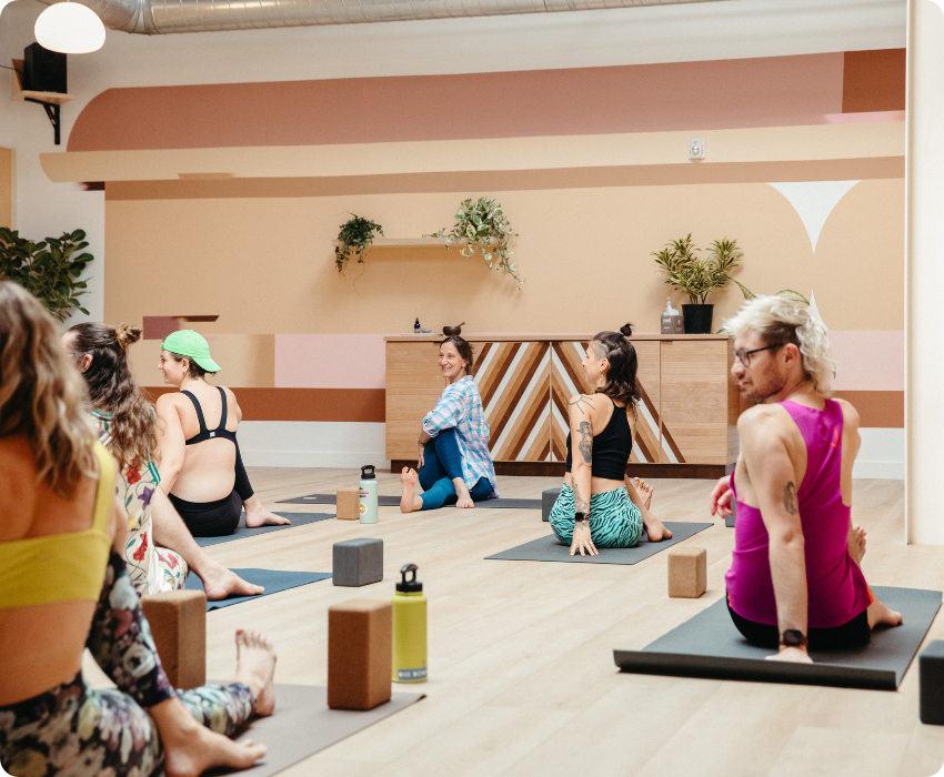 Yoga teacher leading students into a seated twist pose in group class in One Down Dog East Hollywood LA
